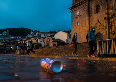 Drink can on wet street by buildings at dusk