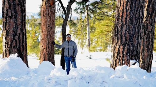 Portrait of man standing on snowy field amidst trees