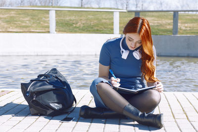 Young woman sitting on retaining wall