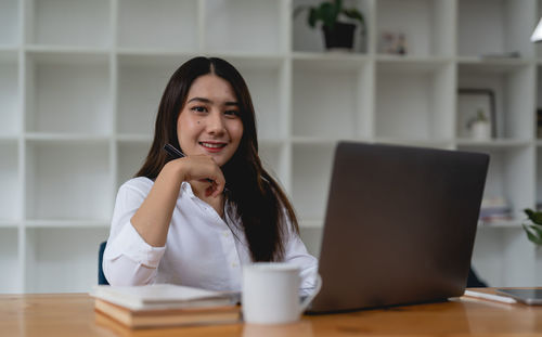 Portrait of young woman using laptop at table