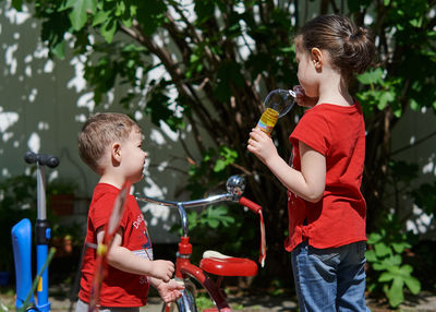 Siblings are playing with soap bubbles in the backyard on a sunny day