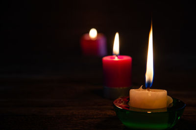 Close-up of lit candles on table in darkroom