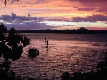 Silhouette people on beach against sky during sunset