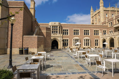 Chairs and tables arranged in front of ucla building during sunny day