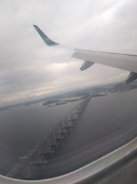 Aerial view of airplane wing over sea against sky