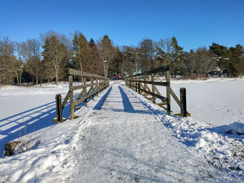 Road leading towards trees against blue sky