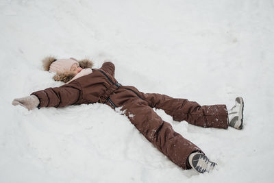 Girl lies in the snow, playing in nature