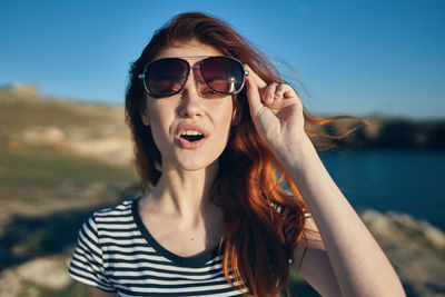 Portrait of young woman wearing sunglasses against sky