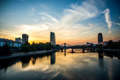 Bridge over river by buildings against sky during sunset in frankfurt, germany 