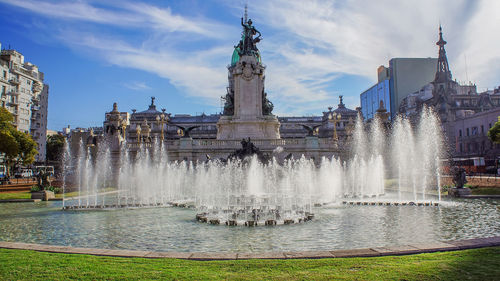 Fountain in city against sky