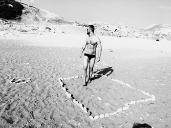 Rear view of shirtless man standing on beach