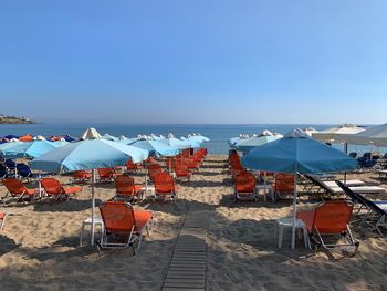 Chairs on beach by sea against clear sky