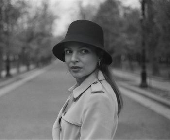 Portrait of young woman standing against car