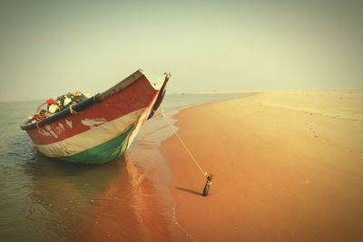 Boat moored on beach against sky