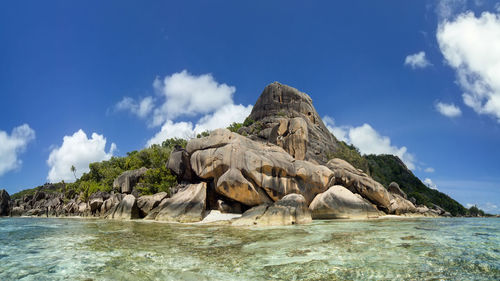 Rock formations by sea against blue sky