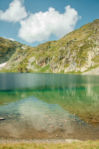 Scenic view of lake by mountains against sky