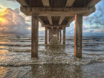 Pier on sea against cloudy sky