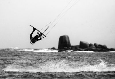 Person kitesurfing over sea against sky