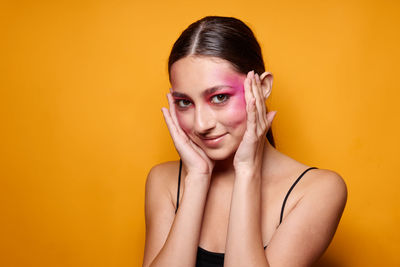 Portrait of young woman against yellow background