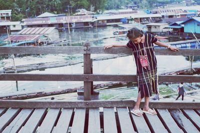 Full length of teenage girl standing against river on pier 