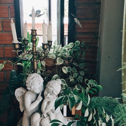 Statue amidst potted plants against window