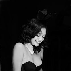 Young woman looking away while standing against black background