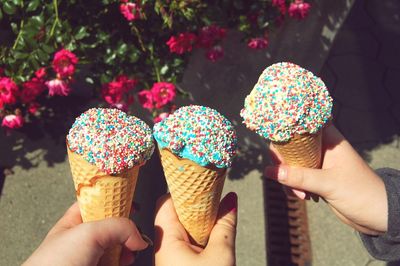 Cropped hands of friends holding ice cream cones