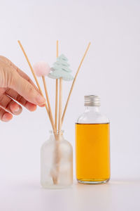 Close-up of hand holding glass bottle against white background