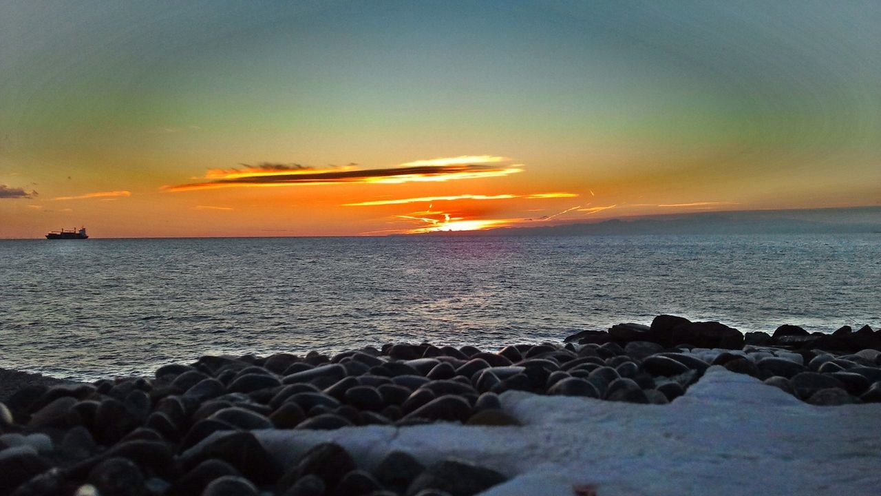 sea, sunset, horizon over water, water, scenics, beach, beauty in nature, tranquil scene, sky, tranquility, shore, rock - object, nature, orange color, idyllic, stone - object, cloud - sky, wave, remote, rock