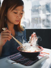 Midsection of woman holding ice cream in bowl on table