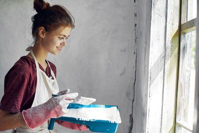 Side view of young woman painting wall