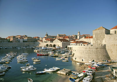 Sailboats moored in city by buildings against sky