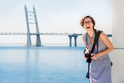 Woman standing on bridge over river against sky