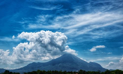 Scenic view of volcanic mountain against blue sky