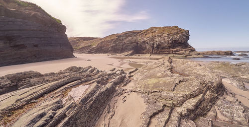 Scenic view of rocks on beach against sky