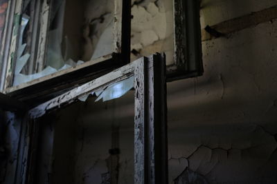 Close-up of broken glass window at abandoned house