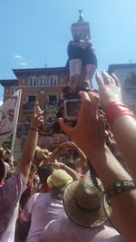 Midsection of woman photographing in city against sky