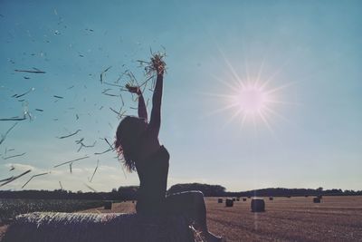 Woman sitting on field against clear sky