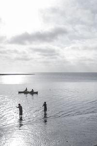 Silhouette people on beach against sky