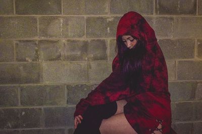 Portrait of beautiful woman standing against red wall