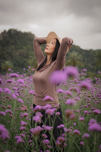 Portrait of woman standing amidst purple flowering plants