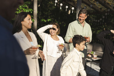 Senior woman shielding eyes while standing by family at patio in back yard