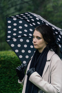 Portrait of young woman standing against trees