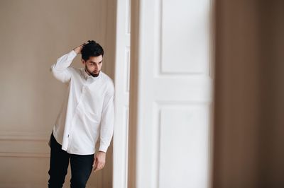 Groom with hand in hair standing by door