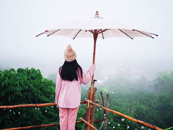 Rear view of woman standing by railing against sky