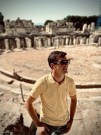 Portrait of young man wearing sunglasses while standing against building