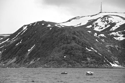 Scenic view of sea by snowcapped mountain against sky