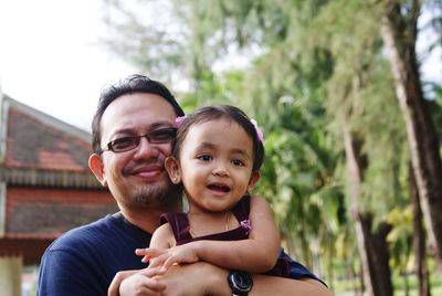 Portrait of happy father and daughter against sky