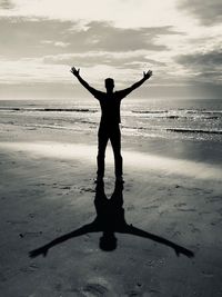 Full length of man with arms outstretched standing at beach