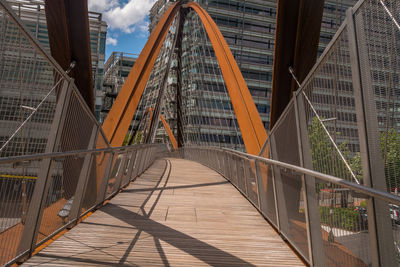 Footbridge over footpath amidst buildings in city